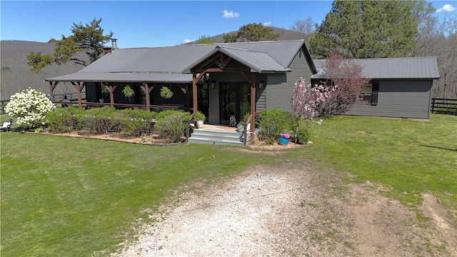 view of front facade with a front yard, fence, and metal roof