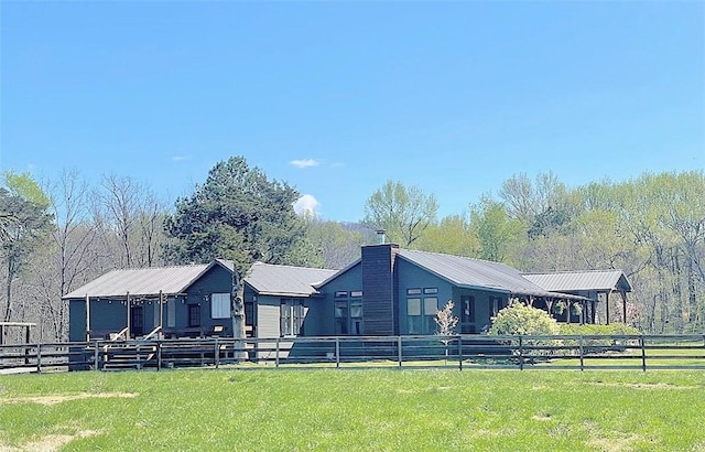 rear view of house with a yard, metal roof, and a chimney