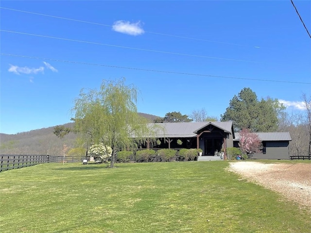 view of front facade featuring metal roof, fence, and a front lawn
