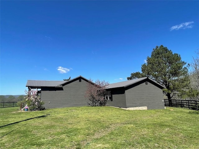 view of property exterior featuring fence, metal roof, and a lawn