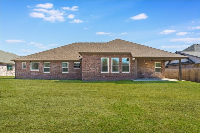 2208 N Carl St, Siloam Springs, AR 72761 - back of property with a shingled roof, a patio area, a lawn, brick siding, and fence