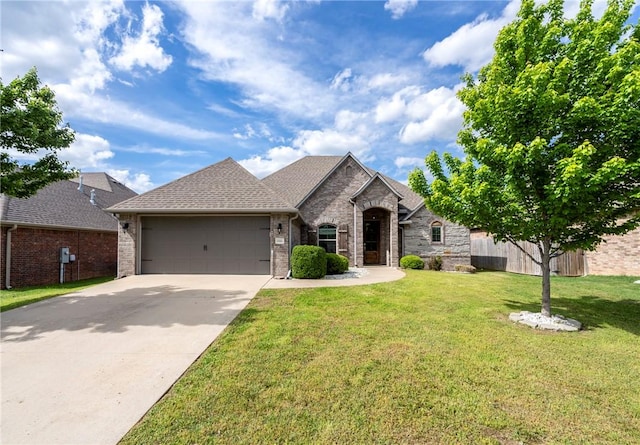 french country inspired facade with fence, an attached garage, brick siding, driveway, and a front yard