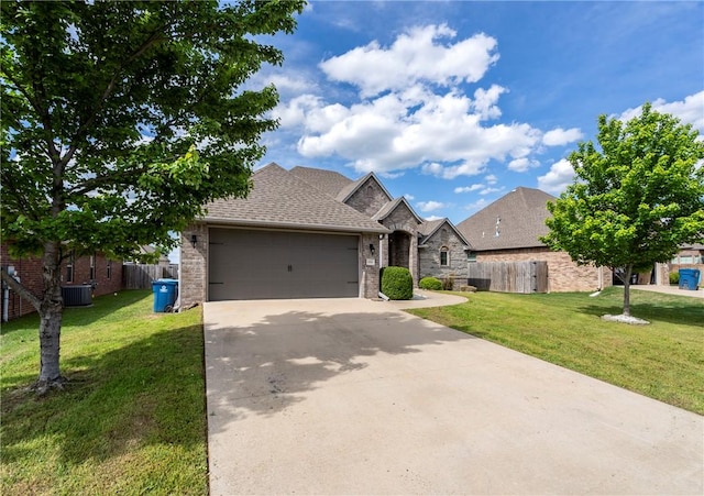 view of front of property with fence, an attached garage, a front lawn, and concrete driveway