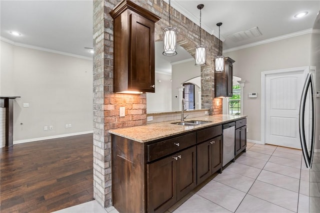 kitchen with a sink, stainless steel appliances, crown molding, dark brown cabinetry, and light stone countertops