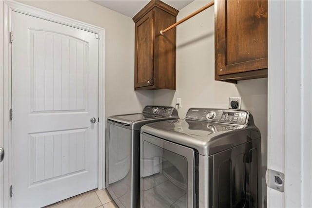 washroom with washer and clothes dryer, cabinet space, and light tile patterned floors