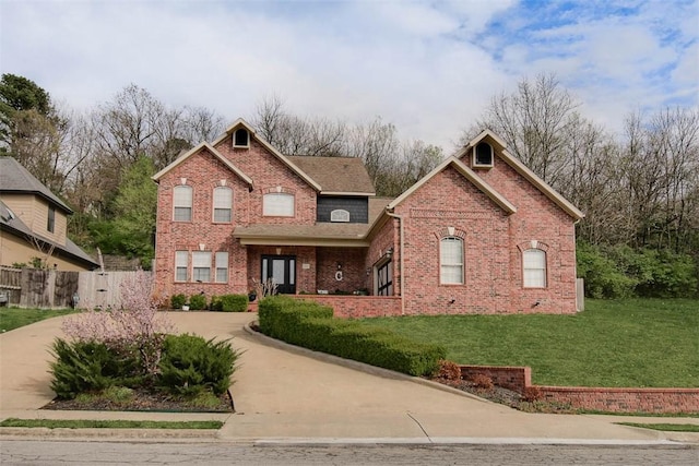 view of front of property with a front yard, brick siding, concrete driveway, and fence