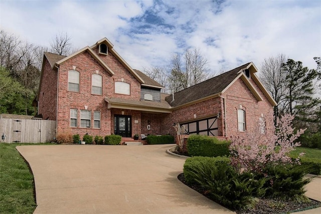 view of front facade with fence, driveway, a garage, and brick siding