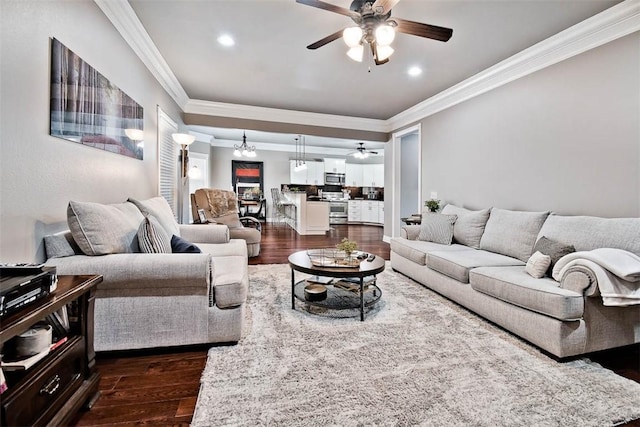 living area with dark wood-type flooring, ornamental molding, recessed lighting, and a ceiling fan