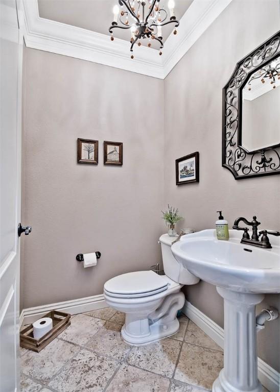 bathroom with baseboards, ornamental molding, toilet, and a notable chandelier
