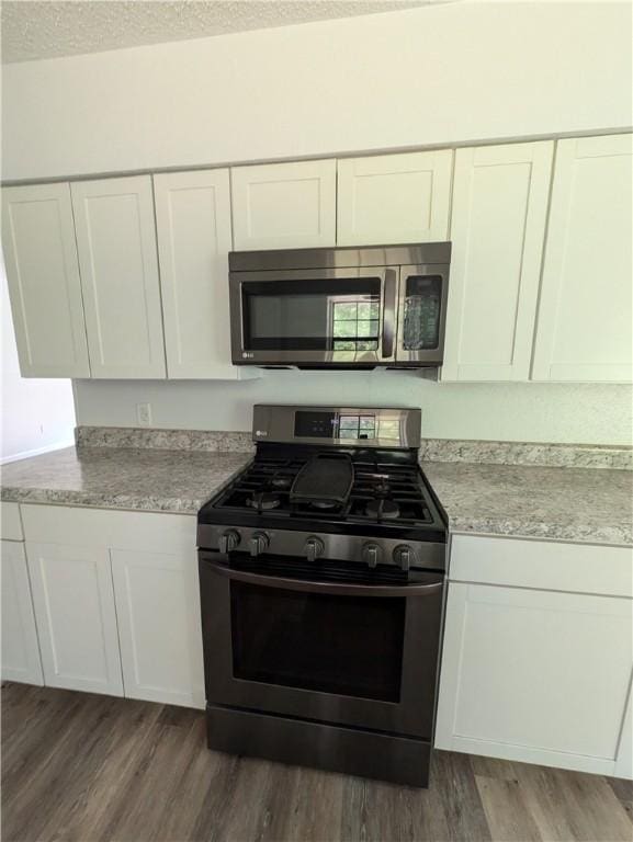 116 Stegall Rd, Clarksville, AR 72830 - kitchen with stainless steel appliances, white cabinets, dark wood-type flooring, a textured ceiling, and light stone countertops
