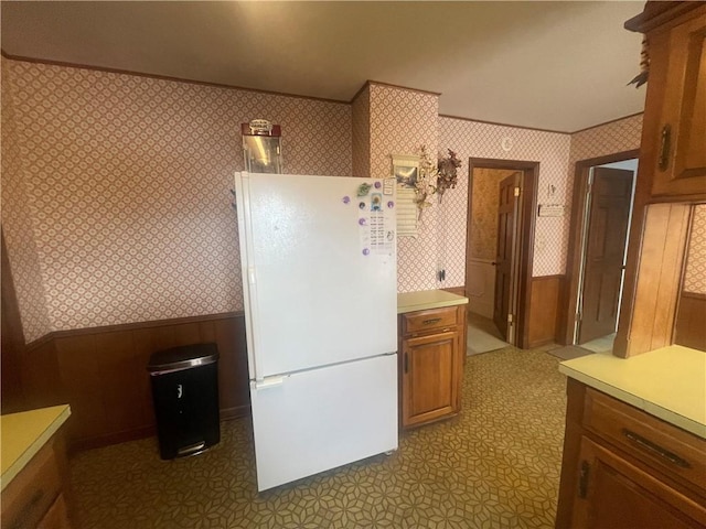803 W Main St, Clarksville, AR 72830 - kitchen featuring freestanding refrigerator, wallpapered walls, a wainscoted wall, brown cabinets, and light countertops
