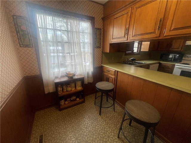 803 W Main St, Clarksville, AR 72830 - kitchen featuring wallpapered walls, a sink, electric stove, light countertops, and brown cabinets