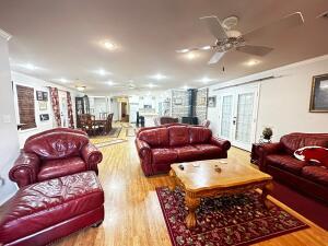 living area with a wood stove, ceiling fan, and wood finished floors