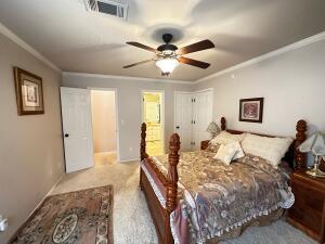 bedroom with ornamental molding, a ceiling fan, and visible vents