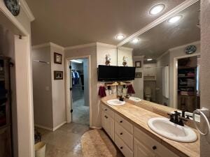 full bathroom with ornamental molding, a spacious closet, recessed lighting, a sink, and double vanity