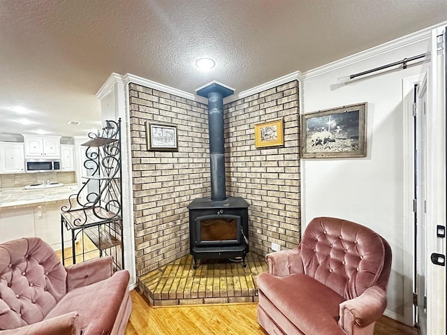 5121 E State Highway 22, Paris, AR 72855 - living area featuring light wood-style flooring, a textured ceiling, a wood stove, and crown molding