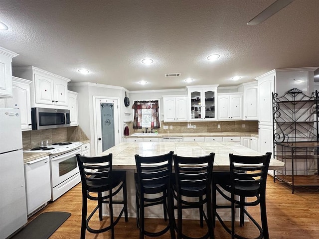 5121 E State Highway 22, Paris, AR 72855 - kitchen with white appliances, a kitchen island, white cabinets, a kitchen bar, and crown molding