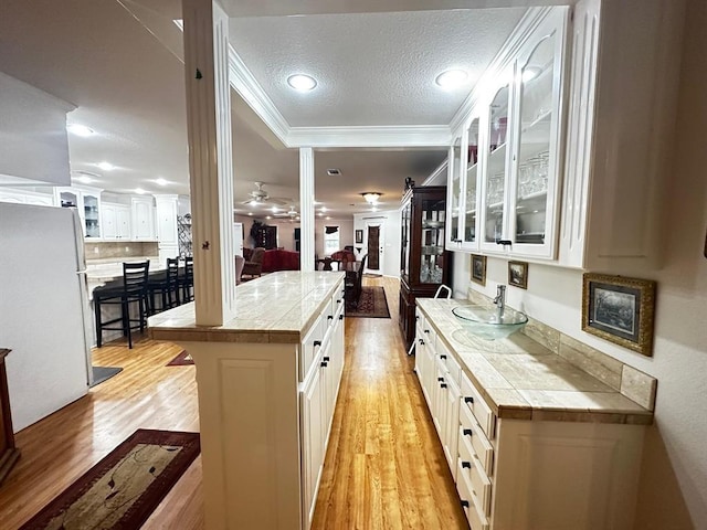 5121 E State Highway 22, Paris, AR 72855 - kitchen featuring light wood finished floors, freestanding refrigerator, glass insert cabinets, white cabinetry, and crown molding