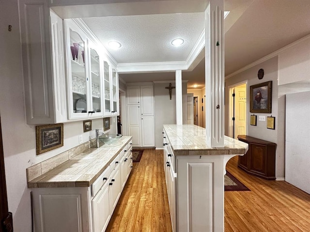 5121 E State Highway 22, Paris, AR 72855 - kitchen featuring light wood finished floors, glass insert cabinets, ornamental molding, white cabinets, and a textured ceiling