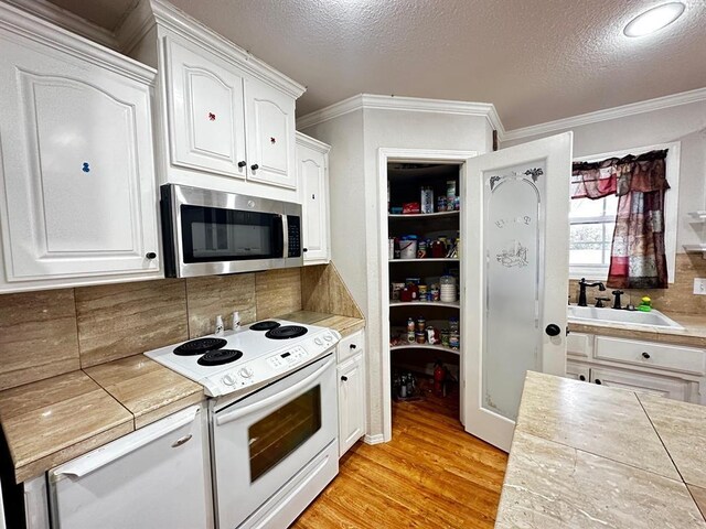 5121 E State Highway 22, Paris, AR 72855 - kitchen with stainless steel microwave, white range with electric stovetop, white cabinetry, tasteful backsplash, and ornamental molding