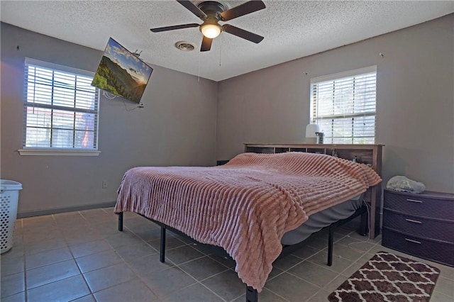 bedroom featuring tile patterned floors, a ceiling fan, visible vents, and a textured ceiling