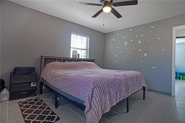 tiled bedroom with a textured ceiling, ceiling fan, and baseboards