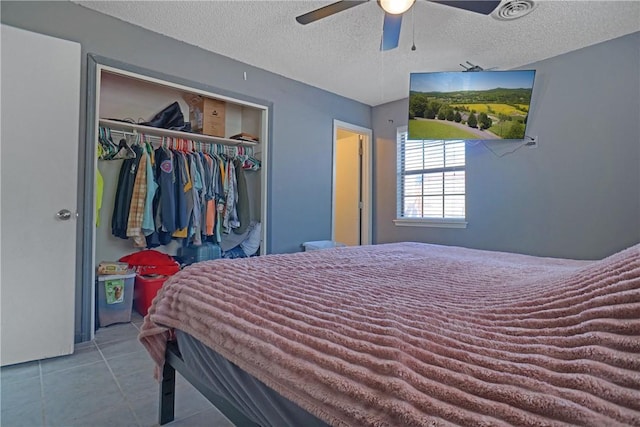 bedroom with a closet, tile patterned flooring, a textured ceiling, visible vents, and ceiling fan