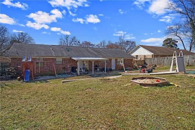 rear view of property featuring a patio area, brick siding, a yard, and fence