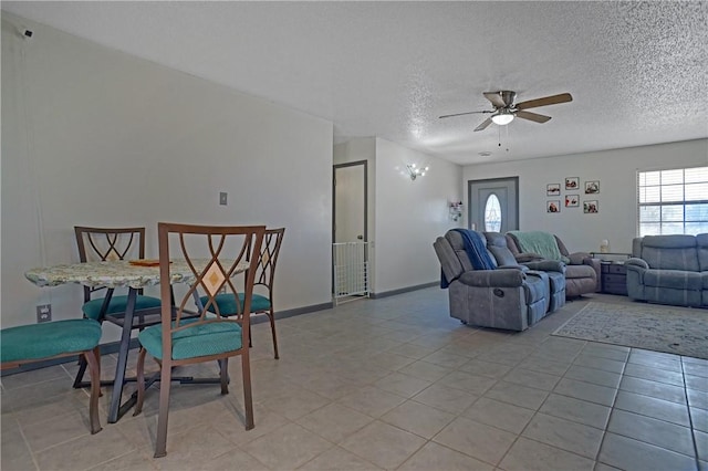 living room with light tile patterned floors, baseboards, a ceiling fan, and a textured ceiling