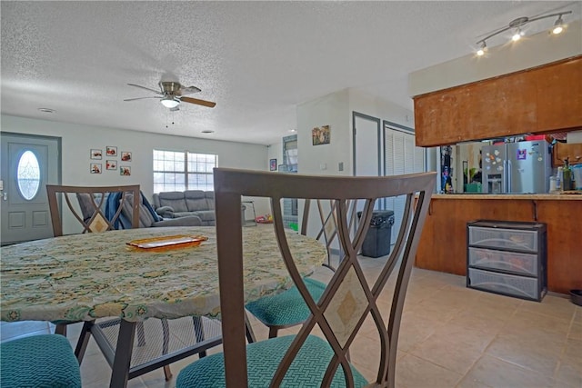 dining space with light tile patterned floors, a ceiling fan, and a textured ceiling