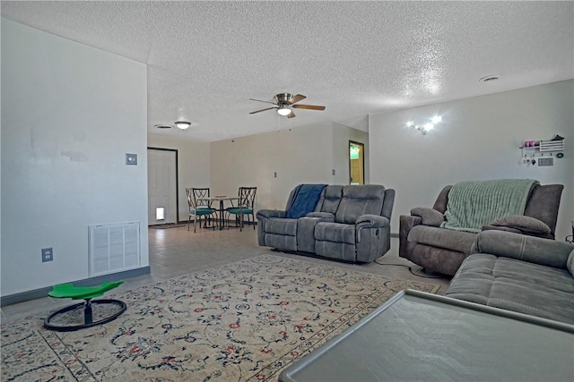 living room with visible vents, ceiling fan, and a textured ceiling