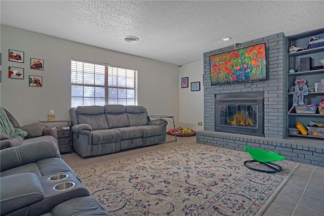 tiled living room with visible vents, a brick fireplace, and a textured ceiling