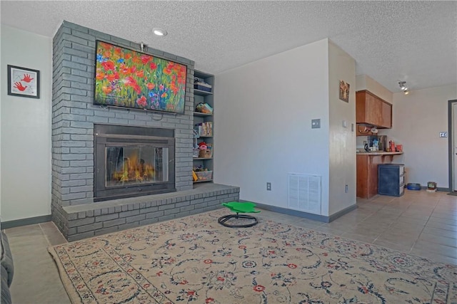 living room with a textured ceiling, a fireplace, and visible vents