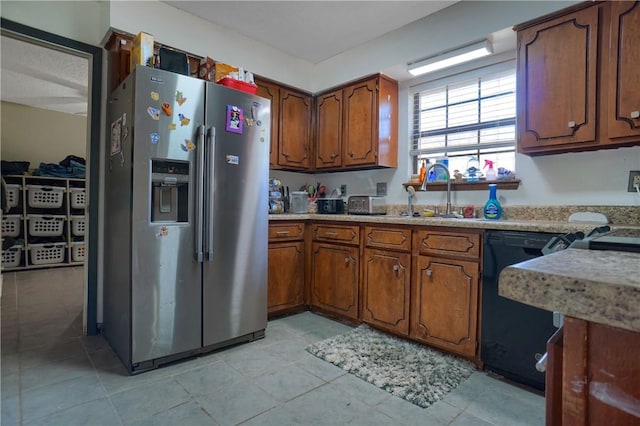 kitchen featuring brown cabinets, stainless steel fridge, black dishwasher, and a sink