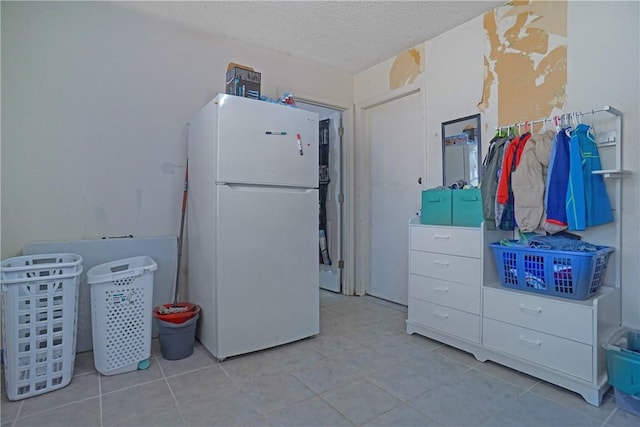 kitchen with tile patterned floors, freestanding refrigerator, and a textured ceiling