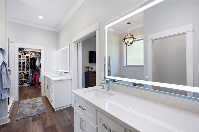 251 Kordsmeier Ln, Morrilton, AR 72110 - bathroom with two vanities, wood finished floors, a walk in closet, a chandelier, and ornamental molding
