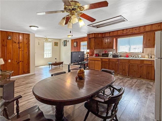 206 Arkansas St, Danville, AR 72833 - dining space with healthy amount of natural light, a ceiling fan, light wood-type flooring, wood walls, and attic access