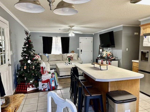 6011 River Rd, Pottsville, AR 72858 - kitchen with stainless steel refrigerator with ice dispenser, light tile patterned flooring, ceiling fan, light countertops, and ornamental molding