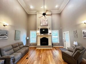 28 Angelfish Ct, Russellville, AR 72802 - living area featuring a towering ceiling, baseboards, a fireplace with raised hearth, ceiling fan, and wood finished floors