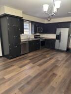 kitchen with an inviting chandelier, white fridge with ice dispenser, dark wood finished floors, dark cabinets, and electric stove