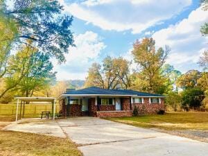ranch-style house featuring a detached carport, a front lawn, and driveway