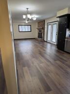 unfurnished living room featuring a large fireplace, a chandelier, wood finished floors, and a wall unit AC