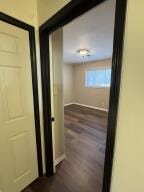 hallway with baseboards and dark wood-style floors