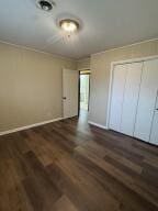 unfurnished bedroom with crown molding, wood finished floors, a closet, and baseboards