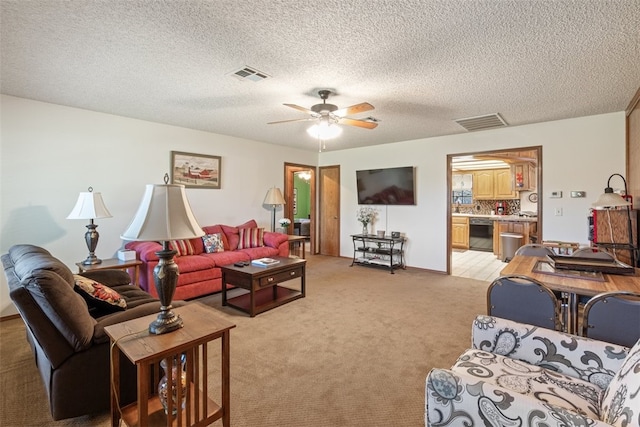 living room featuring a ceiling fan, light carpet, a textured ceiling, and visible vents