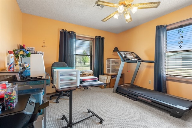 exercise room featuring visible vents, a textured ceiling, carpet, and ceiling fan