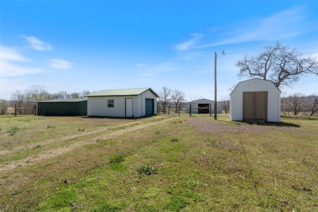 view of yard featuring an outbuilding, driveway, and fence