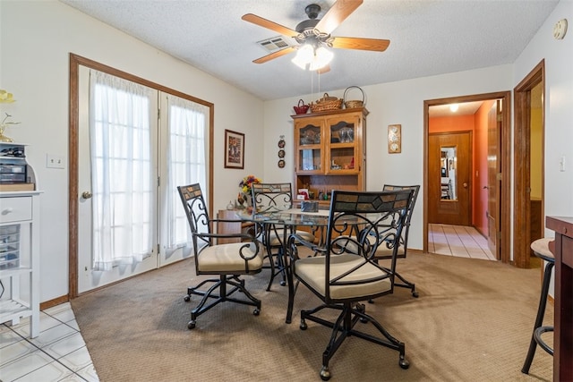 dining space featuring ceiling fan, a textured ceiling, light colored carpet, and visible vents
