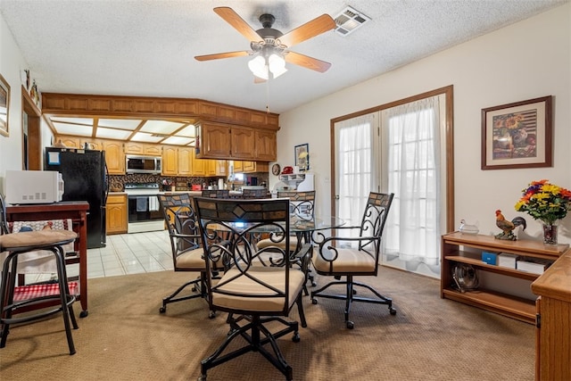 dining room with light carpet, a textured ceiling, visible vents, and a ceiling fan