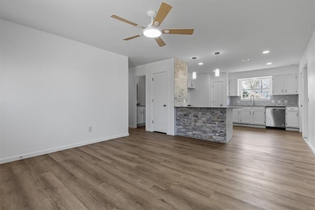 unfurnished living room featuring a sink, baseboards, recessed lighting, a ceiling fan, and wood finished floors